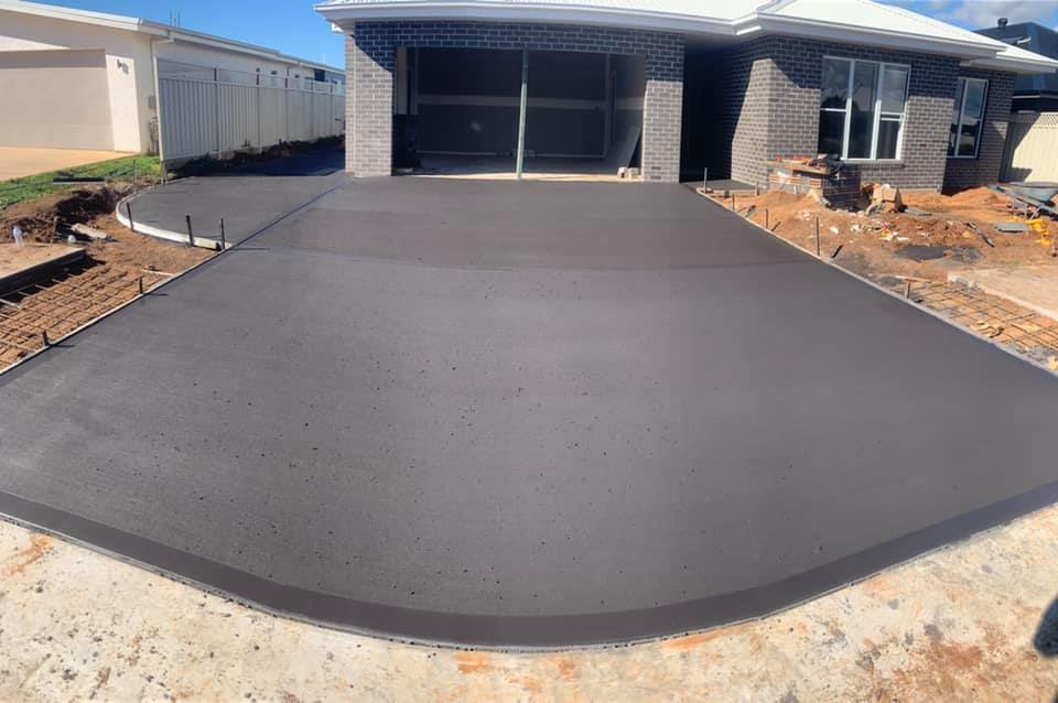 A wide finished concrete driveway sweeping up to a new double garage