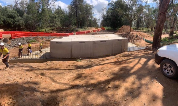 A crew beside a run of precast box culverts set into a formed base