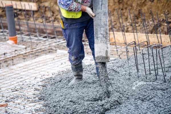 Wet concrete running from a pump hose into a steel-fixed wall footing