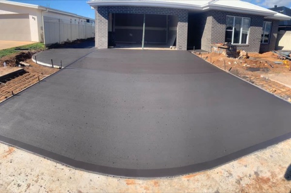 A finished driveway slab curving up to a new double garage