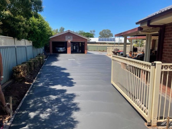 A wide driveway beside a fenced verandah leading to a brick garage
