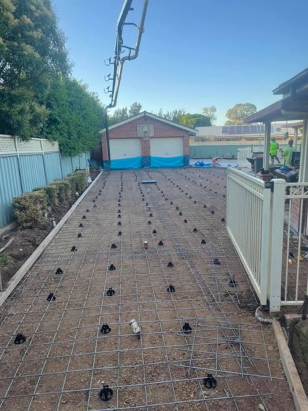 Steel mesh on bar chairs laid out across a formed driveway bay