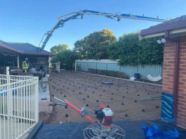 A power trowel sitting on plastic sheeting with a pump boom overhead