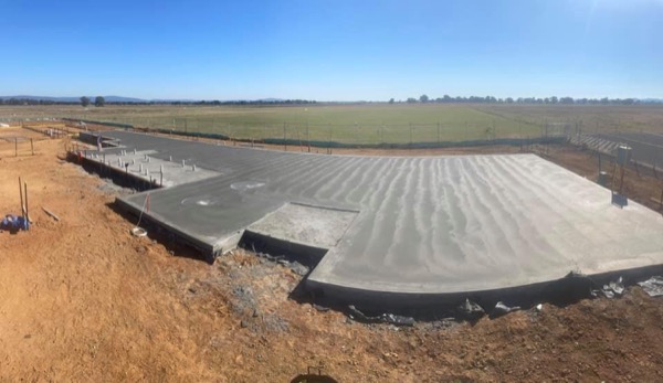 A broom-finished rural slab poured against cut red soil