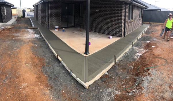 A concrete apron poured around the corner of a new brick house