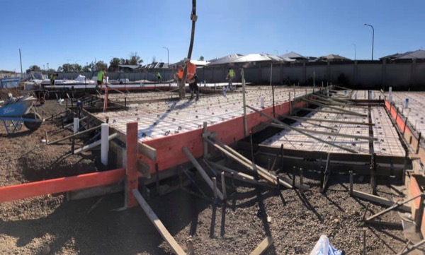 A large commercial slab formed and steel-fixed with crew working along the far edge