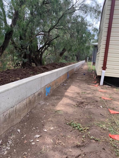 A poured retaining wall running along a boundary beside a house